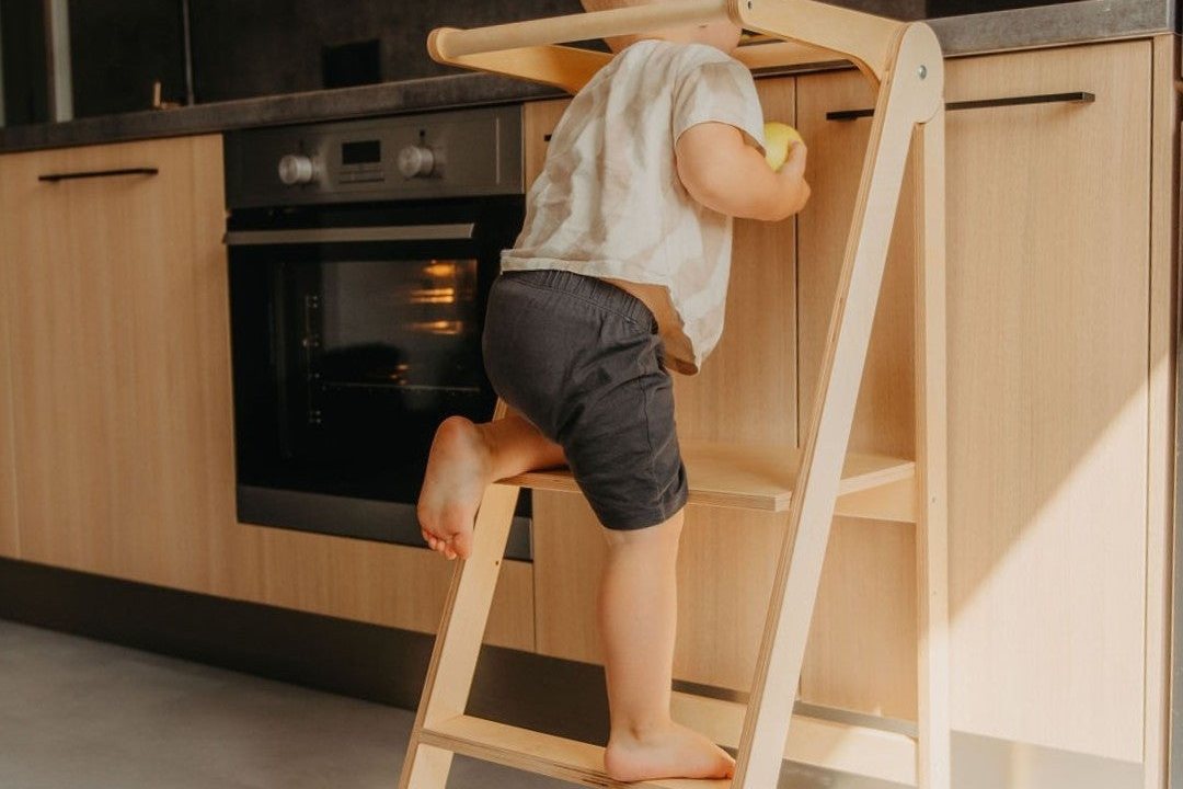 Enfant qui monte sur une tour d'observation pliable en bois, dans une cuisine