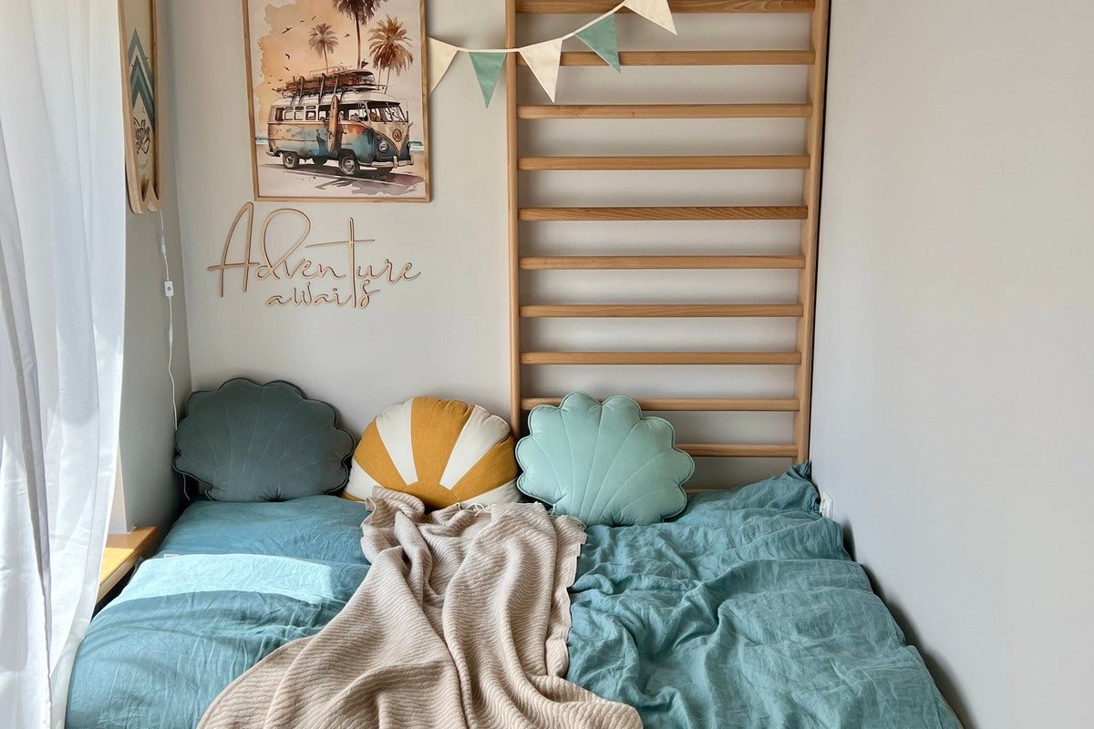 Coin nuit douillet avec coussins coquillages, plaid et fanions sous une inscription murale en bois