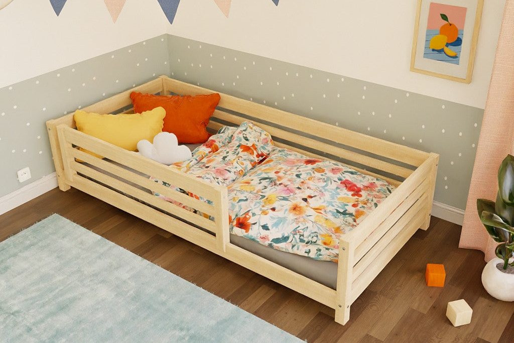 Lit au sol en épicéa avec barrières, coussins et jouets sur le couchage