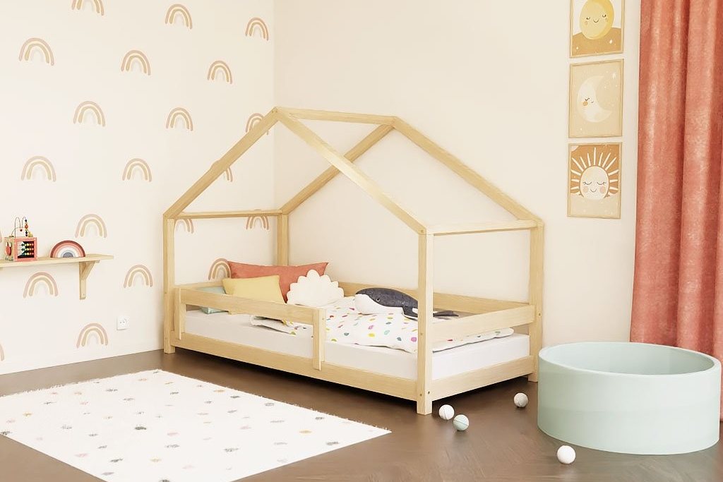 Lit cabane bas en bois naturel dans une chambre d'enfant, au pied d'un tapis