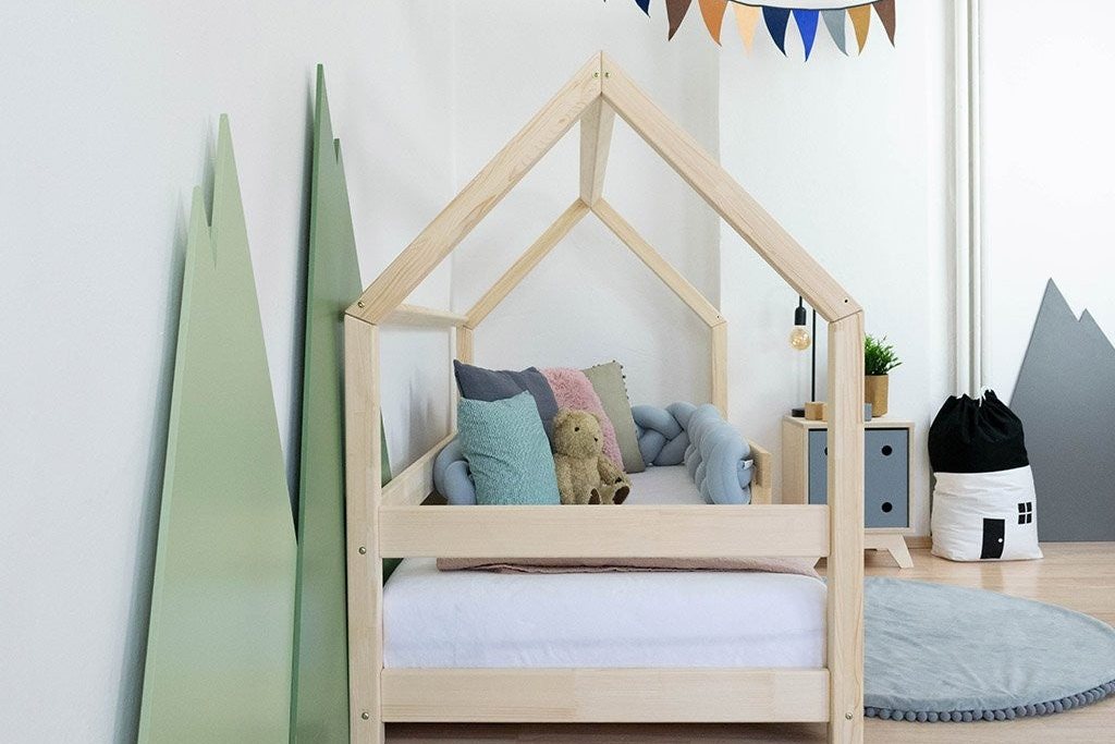 Petit lit cabane en bois avec fanions, dans une chambre claire
