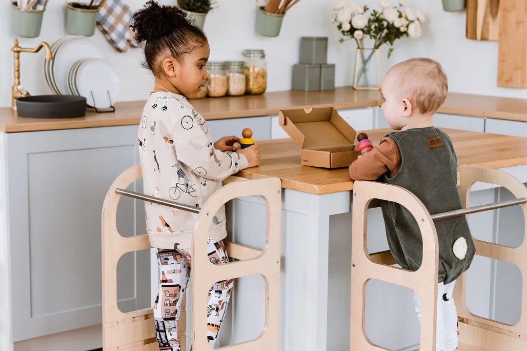Deux enfants debout sur des tours d'observation au plan de travail de la cuisine