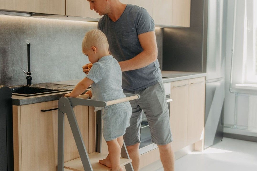 Un parent et son enfant cuisinent ensemble, l'enfant sur une tour d'observation