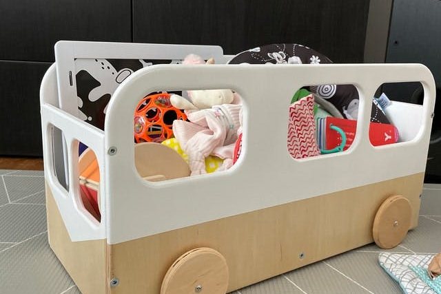 Coffre à jouets en bois sur roulettes en forme de bus, rempli de peluches