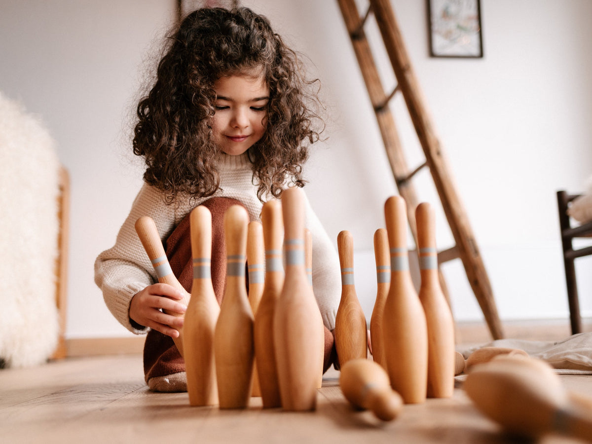 Une petite fille joue avec des quilles en bois Wooden Story