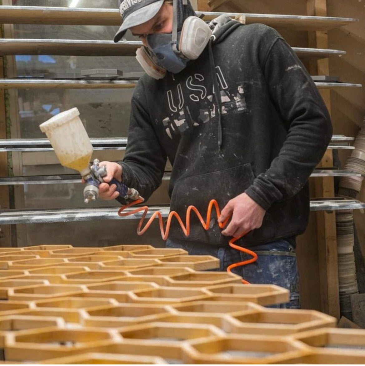 Un artisan d'Ewart Woods vernit au pistolet des pièces en bois dans l'atelier