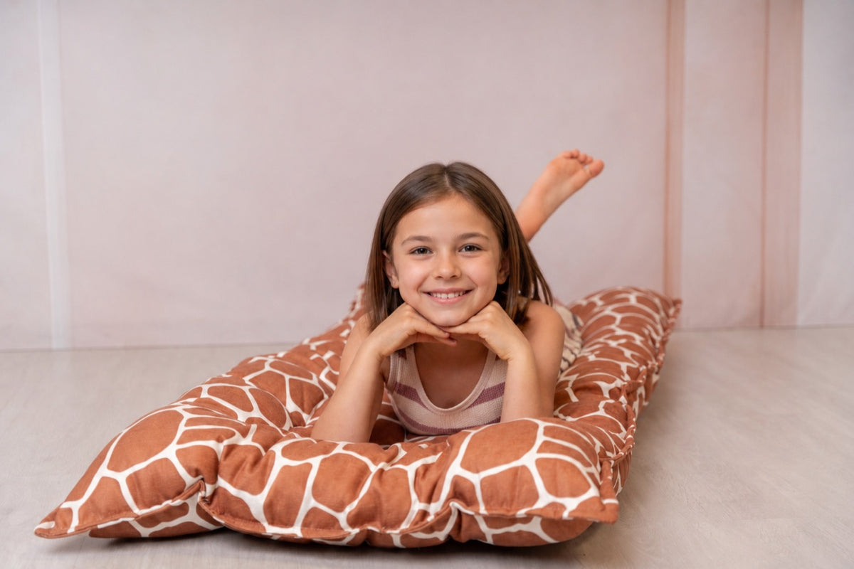 Une fillette allongée sur un coussin de sol matelassé bees&blooms