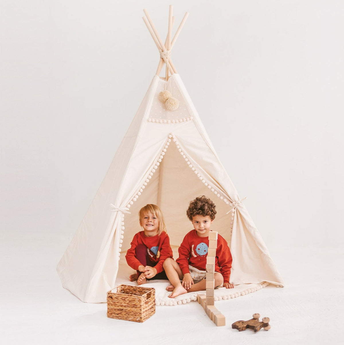 Deux enfants jouent dans un tipi Minicamp écru à pompons